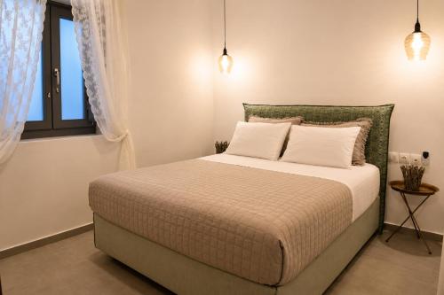 a bedroom with a bed with white pillows and a window at Mare Bay in Adamantas