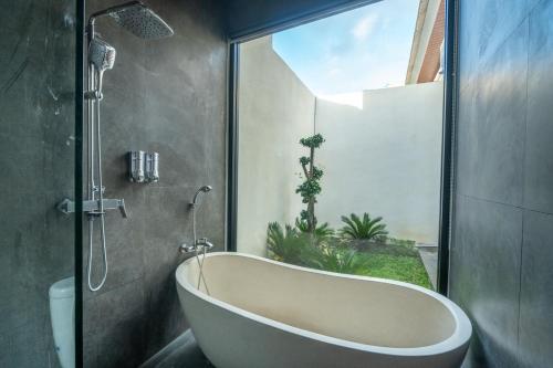 a bath tub in a bathroom with a window at Sawitri Ubud Villas in Blahbatu