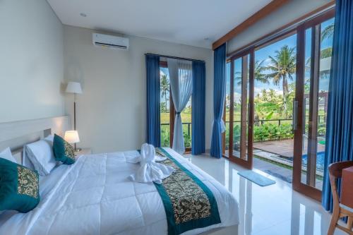 a bedroom with a white bed with a view of the ocean at Sawitri Ubud Villas in Blahbatu