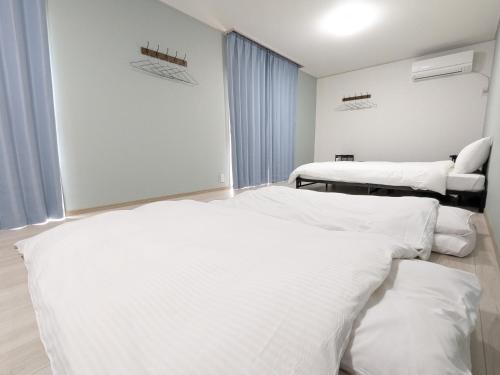 two beds in a hospital room with white sheets at Joynest TAKAMATSU in Takamatsu