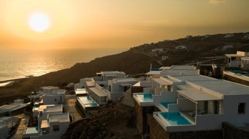 a group of white buildings on a hill next to the ocean at Epic Blue Mykonos in Houlakia