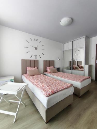 two beds in a room with a clock on the wall at Być Morze in Mrzeżyno