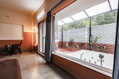 a bathroom with a tub and a large window at Nitz the loft in Pondicherry