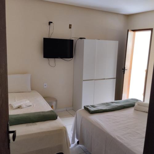 a room with two beds and a television on the wall at Pousada Mandala in Palmeiras
