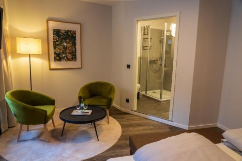 a room with two chairs and a table and a shower at Hotel Restaurant St. Germanshof in Bobenthal