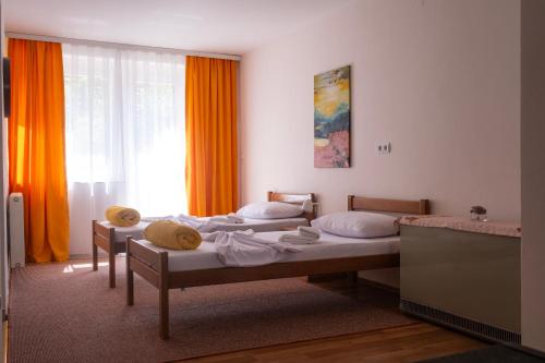 two beds in a room with orange curtains at Rron's House in Prizren