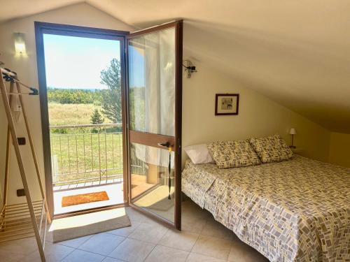a bedroom with a bed and a sliding glass door at AgroVerde Apartment a 10 minuti da Alghero in Tottubella