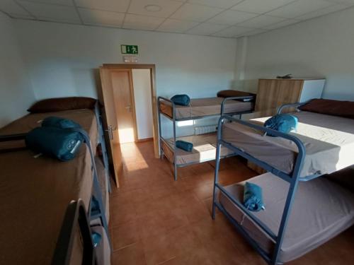 a room with three bunk beds and a room with a door at Albergue Niu d'Estels in Albiol