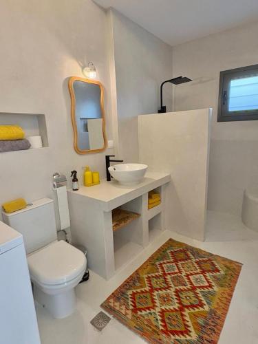 a bathroom with a toilet and a sink and a mirror at The Izi House in Egina