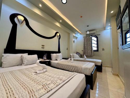 a hotel room with two beds with swans on them at Hotel G in Sūhāj