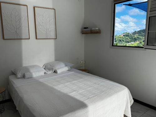 a bedroom with a white bed with a window at Studio Colibri vue mer in Quartier Morne Acajou