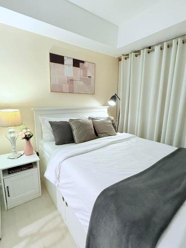 a bedroom with a large white bed and a night stand at SM Bicutan Quick Staycation PH in Manila