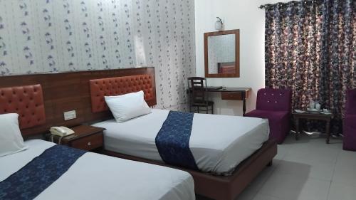 a hotel room with two beds and a chair at Hotel Rest INN in Lahore