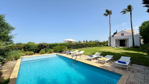 a swimming pool with chairs and a house at Dunas - Private Pool - 8 Guests - Albufeira in Albufeira