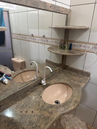 a bathroom with a sink and two faucets on a counter at Casa com Quartos compartilhados in Rio Branco