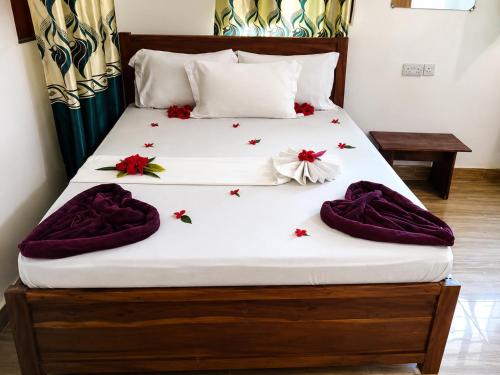 a bed with purple blankets and flowers on it at primavera jambiani in Mfumbwi