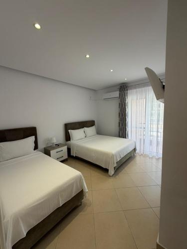 a bedroom with two beds and a large window at Himara Royal Hotel in Himare
