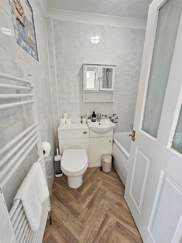 a white bathroom with a toilet and a sink at Holly Cottage in Edwinstowe