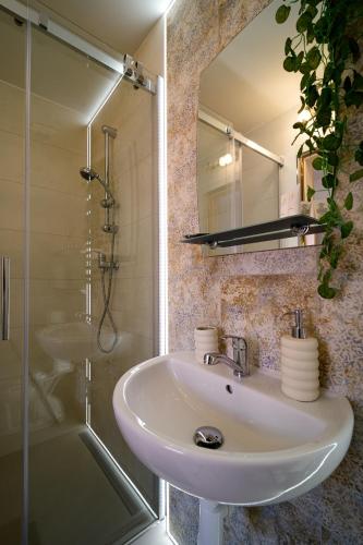 a bathroom with a sink and a shower and a mirror at PB Apartments in Spišská Nová Ves