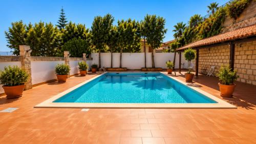a swimming pool in a backyard with potted plants at Aloha Village - Bed&Pet in Messina