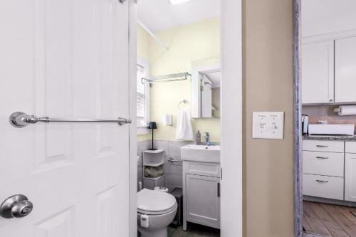 a white bathroom with a toilet and a sink at Waterfront Studio - Bay Views, Steps to Comm St in Provincetown