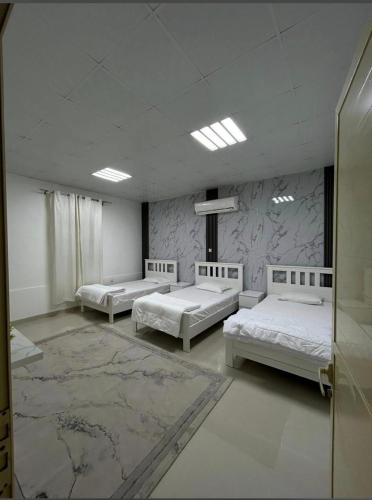 a large room with three beds and a rug at استراحة الصقر in Khor Fakkan