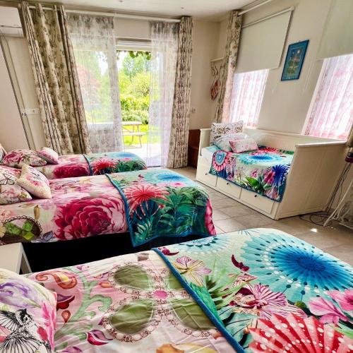 a room with three beds with flowers on them at Rooi Bij de Knoptoren B&B in Sint-Oedenrode