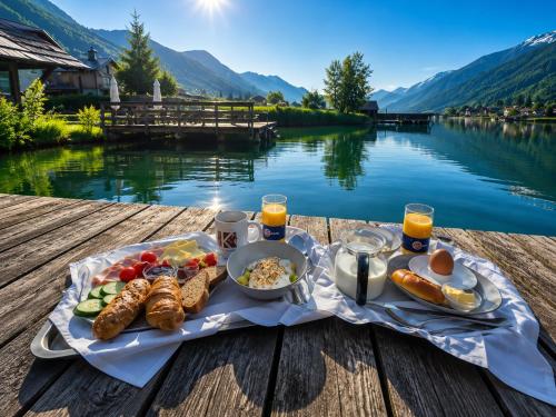 a tray of breakfast food on a table next to a lake at Der Kaerntnerhof am Weissensee, SeeHotel & SeeApartments direkt am See in Weissensee