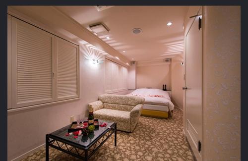 a bedroom with a bed and a chair and a table at ホテルヴェローナ in Yokohama