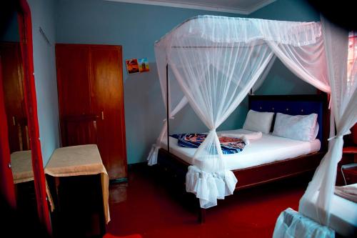 a bedroom with a canopy bed with white curtains at Kilimanjaro Simba Lodge in Moshi