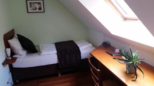 a small bedroom with a bed and a desk at Ellenbergs Restaurant & Hotel in Heßheim