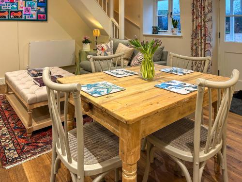 a wooden dining room table with chairs and a couch at Grange Cottage in Langham