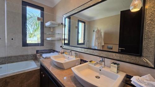 a bathroom with two sinks and a large mirror at Villa Yacout Marrakech -Private Pool in Sraghna