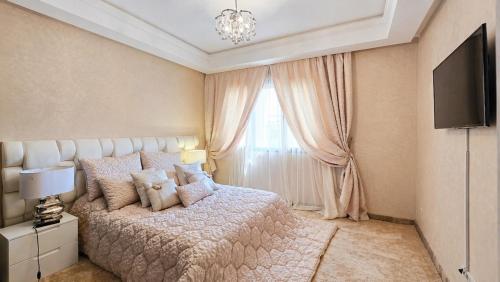 a bedroom with a bed and a tv and a window at Villa Yacout Marrakech -Private Pool in Sraghna