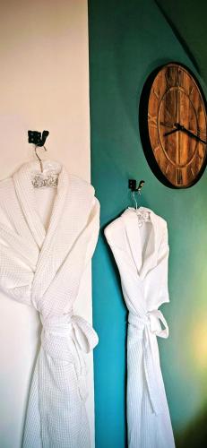 two white dresses hanging on a wall with a clock at Rezen Villas in Lorca