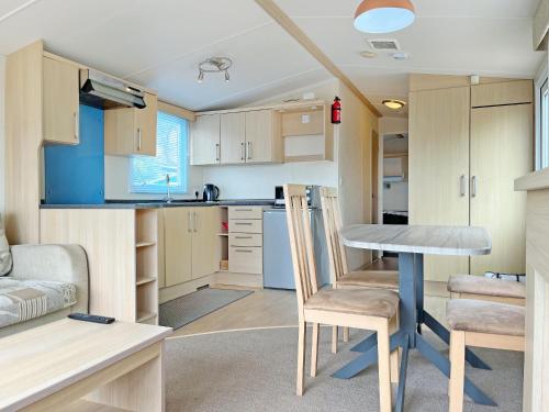 a small kitchen with a table and chairs in a caravan at Forest Edge - Uk51739 in Oakmere