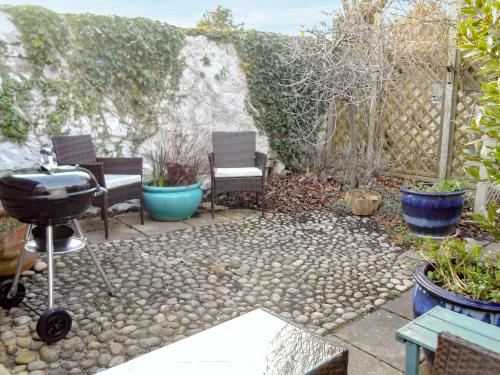 a backyard with chairs and a grill and plants at Fisher Gallery in Pittenweem