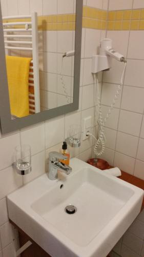 y baño con lavabo blanco y espejo. en Ellenbergs Restaurant & Hotel en Heßheim