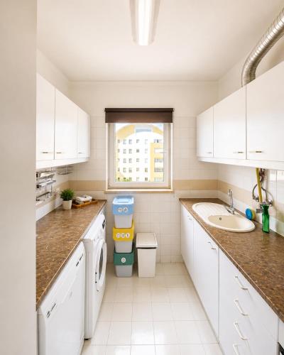 a kitchen with white cabinets and a sink and a window at Lisbon Lux T1 Pool Gym Tennis AC - Pouso dos Anjos Apartment in Lisbon