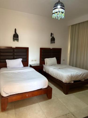 a bedroom with two beds and a chandelier at Carlton Luxury Villa in Sharm El Sheikh