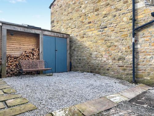 a bench sitting next to a building with a blue door at Pletts Barn in Grassington