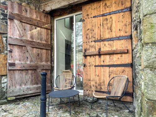 two chairs and a table in front of a wooden wall at Pletts Barn in Grassington