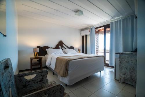 a bedroom with a large bed and a large window at Arambare Buzios Hotel in Búzios