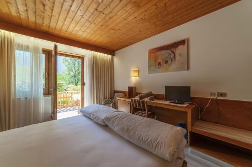 a bedroom with a bed and a desk with a computer at Hotel St. Pankraz in San Pancrazio dʼUltimo