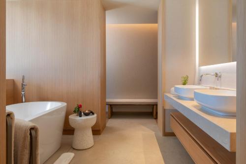a bathroom with two sinks and a tub and a toilet at Legacy Ithos Boutique Hotel in Porto Santo