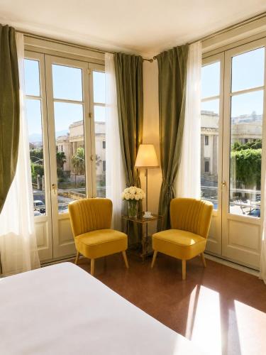 a bedroom with a bed and two chairs and windows at ISOLA - Smart Accomodation in Messina