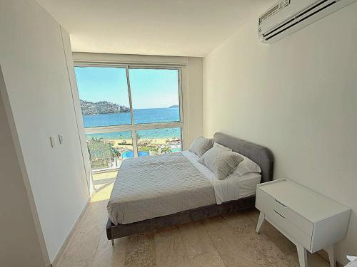 a bedroom with a bed with a view of the ocean at Playa Acapulco Espectacular Apartment in Acapulco