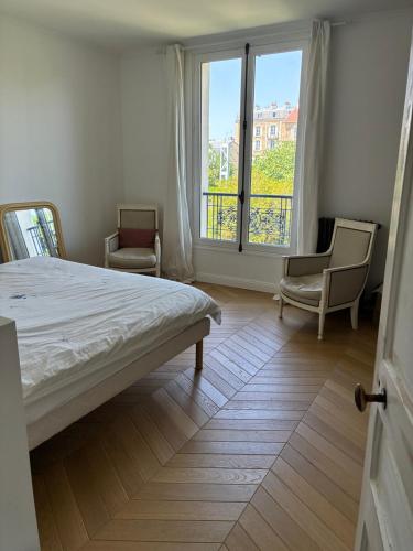 a bedroom with a bed and two chairs and a window at Grande maison familiale rénovée en 2025 in Versailles