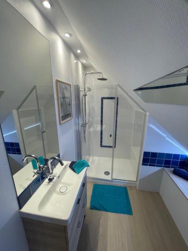 a white bathroom with a shower and a sink at Gite Gavotte in Concarneau