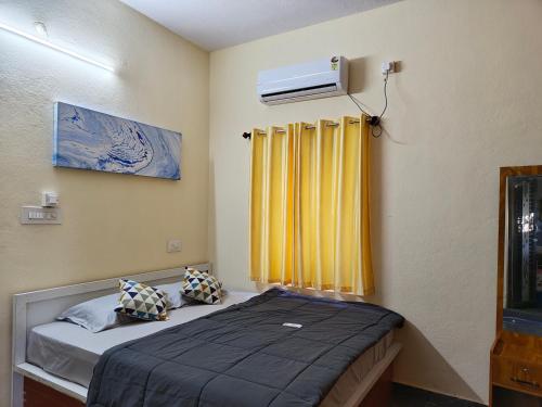 a bedroom with a bed and a yellow curtain at Hamsa Farmstay - 3BHK AC homestay in Mysore
